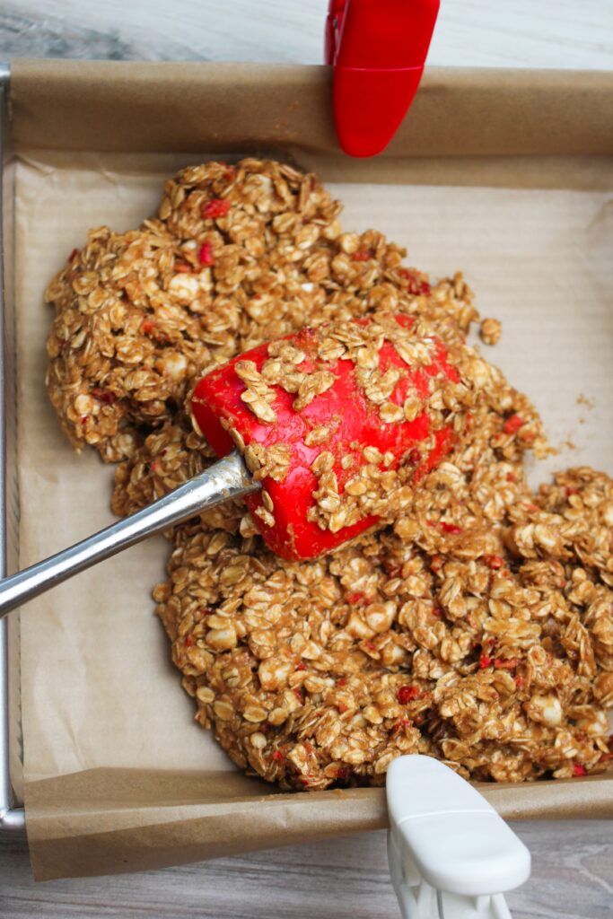 Spreading the mixture into a pan in an even layer with a spatula.