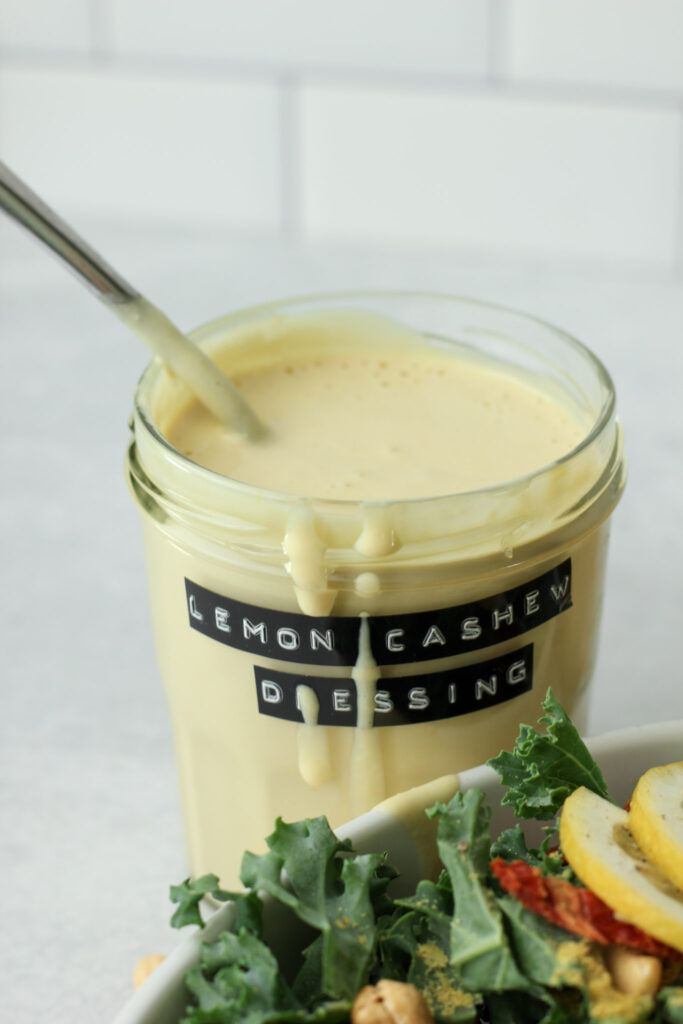 A spoon has been placed into the jar of dressing and is spilling over the side.