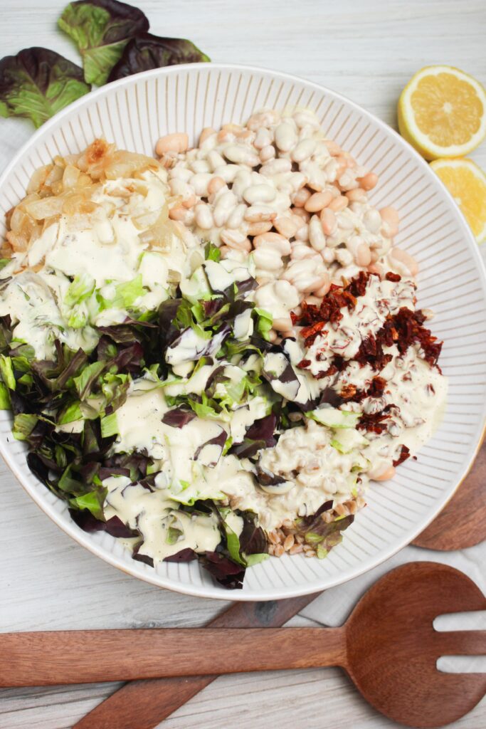 THe dressing has just been poured over the top of the salad and is ready to be tossed.