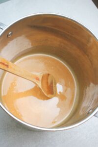 Mixing the warm melted butter with the melted peanut butter in a large pan over the stove. 