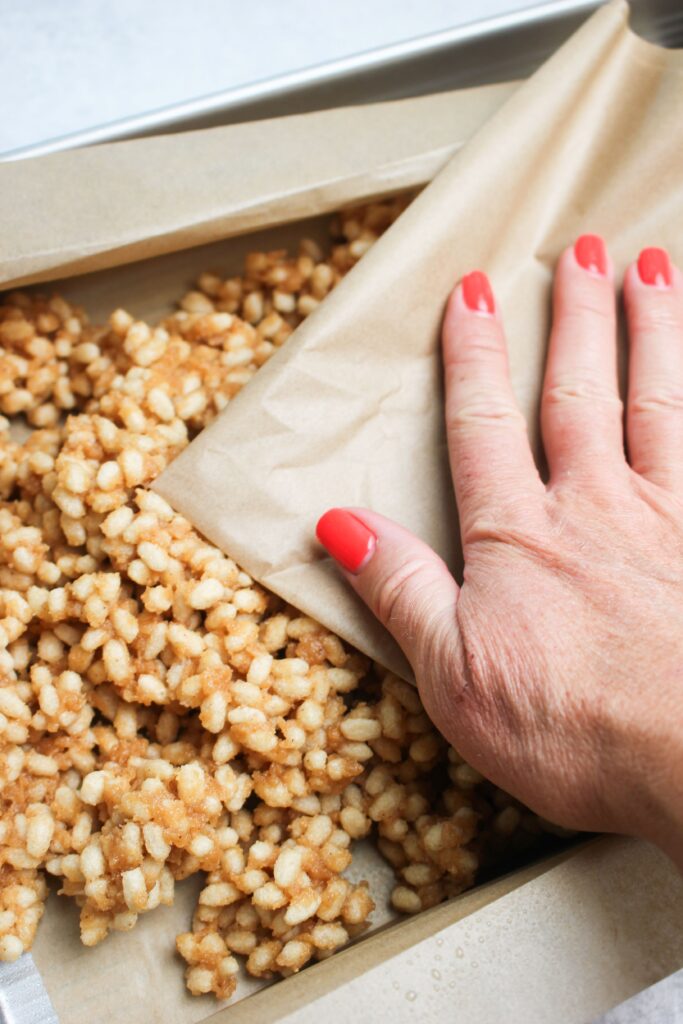 Pressing the peanut butter mixture into the bottom of a pan. 