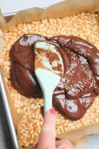 Spreading the chocolate over the top of the rice krispie treats.