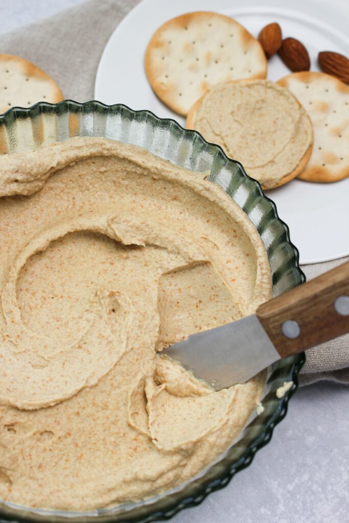 Spreading almond dip onto a cracker.