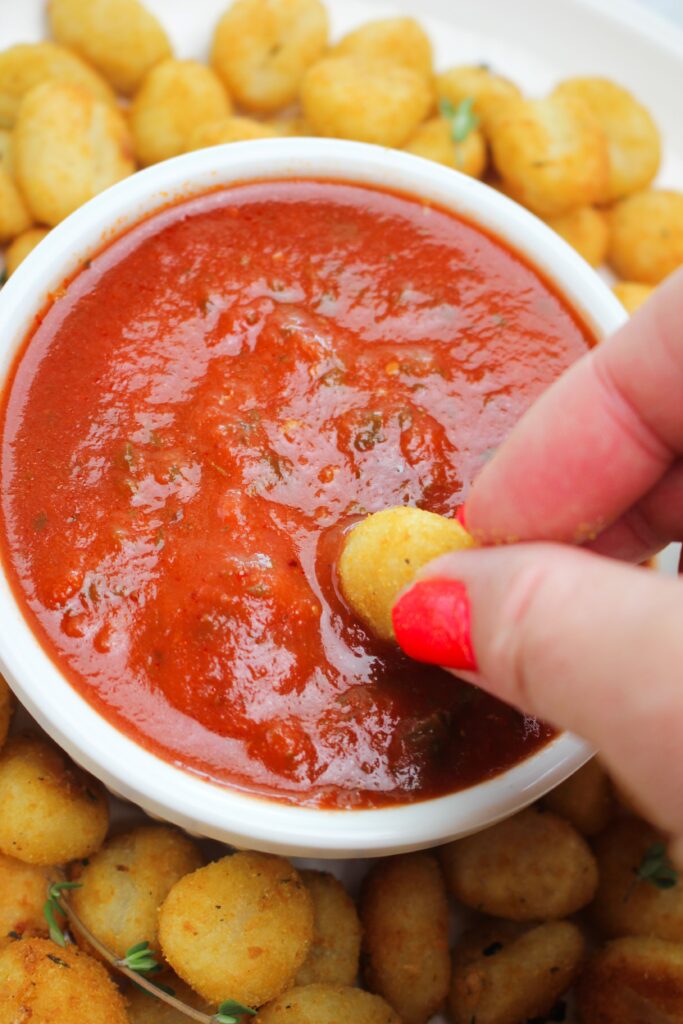 Dipping an air fried gnocchi into marinara sauce.