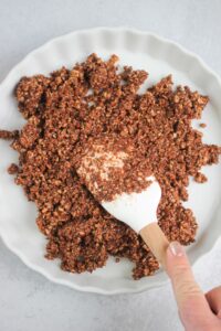 Spreading the crust into the pie pan with a spatula.