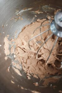 The finished whipped cream in the bowl of a stand mixer.