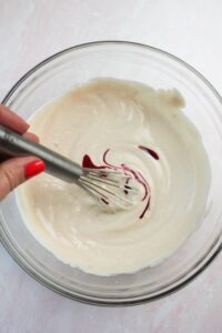 Stirring in the red food dye into the yogurt mixture.