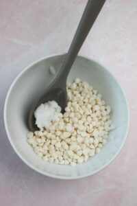 A small bowl of white chocolate chips and coconut oil is ready to go into the microwave to melt.