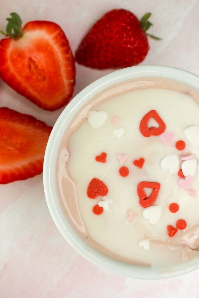 An up close picture of one pudding cup with strawberries next to it.