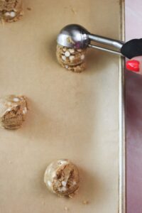 Scooping balls of dough onto the lined cookie sheet.