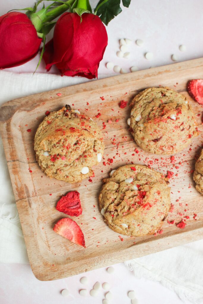 The cookies are on a platter next to roses and are ready for a Valentine's celebration.