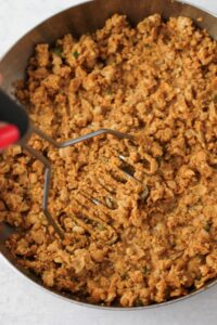 Smashing the chickpea mixture with a potato masher.