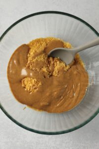 The crushed cornflakes, peanut butter, and maple syrup in a bowl.