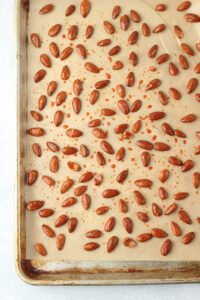 The almonds are covered in the sweet and spicy mixture in a pan and are ready to go into the oven.