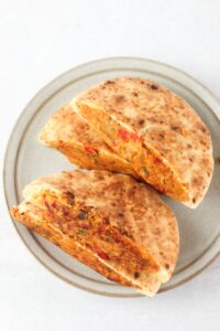 The falafel-stuffed pita pockets have been grilled and are on a plate.