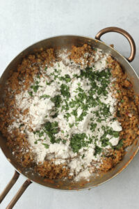 Adding the flour and parsley to the pan.