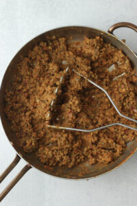 Mashing the lentil mixture with a potato masher.
