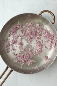The onion being cooked in a pan.