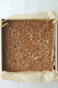 The oat mixture is poured into a square pan and spread out evenly.