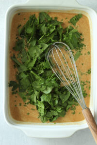 The spinach and chives have been added to the casserole dish.