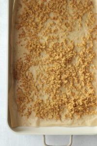 Half of the quinoa has been cooked until crispy on a baking sheet.