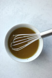 The dressing has been whisked in a small bowl.