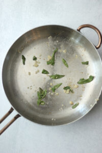 The sage and garlic are cooking on a pan.