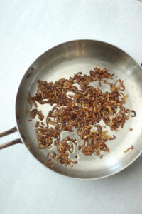 The crispy shallots are cooking on a pan.