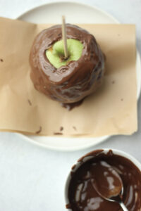 The caramel apple has been covered in melted vegan chocolate.