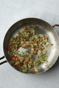 Sautéing onion, carrot, and celery in a frying pan.
