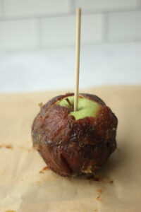 The caramel apple has been wrapped in the sheet of dates.