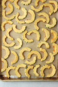 The Delicata squash moons are on a baking sheet, ready to be roasted.