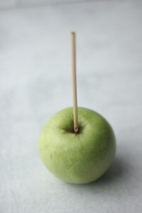 A skewer has been pressed into a Granny Smith apple.