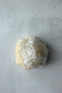 The dough has been rolled into a ball and wrapped in plastic wrap.