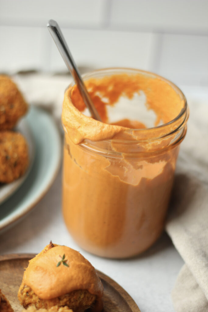 The sauce is in a mason jar and has been spooned onto a veggie ball.