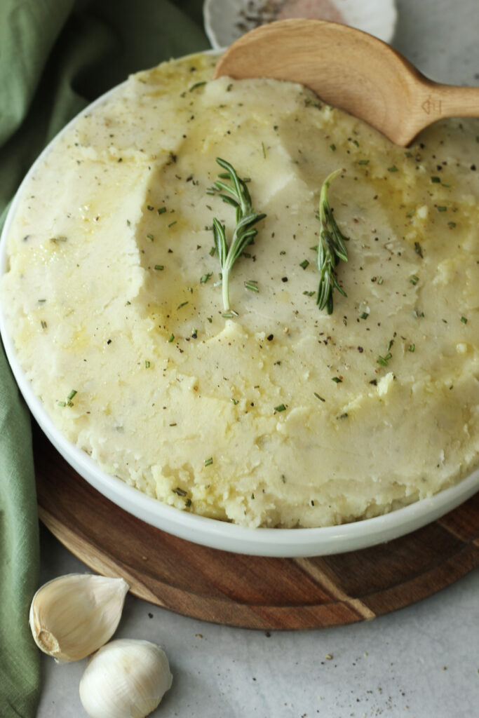 The vegan garlic herb mashed potatoes are ready to be served in a large dish.