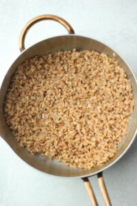 The farro is finished cooking in a saucepan.
