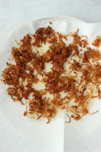 The cooked shallots are cooling on a paper towel.