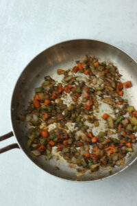 The herbs, seasonings and garlic have been added to the frying pan.