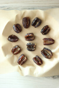 The soft dates have been opened and laid onto parchment paper. 