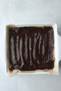 The ganache has been spread over the top of the flattened rice krispie mixture.