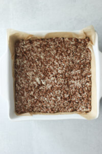 The rice krispie mixture has been flattened into a square casserole dish.