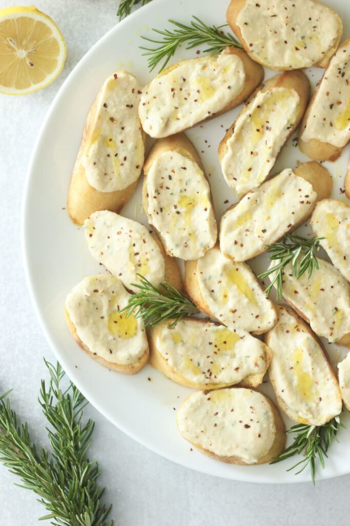 A close-up picture of this rosemary white bean crostini on a large white plate.