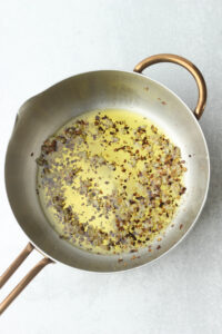 The garlic, olive oil, and red pepper flakes are simmering in a saucepan.