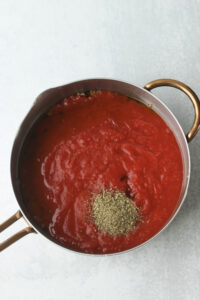 The crushed tomatoes, tomato sauce, and Italian seasoning have been added to the saucepan.