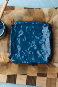 The blue frosting has been spread over the brownies.