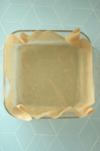 The 8x8 pan has been lined with parchment paper.