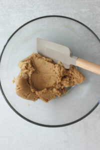 The dough has been mixed in a clear glass bowl with a spatula.