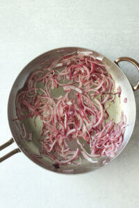 Sautéing the red onion and avocado oil in a frying pan.