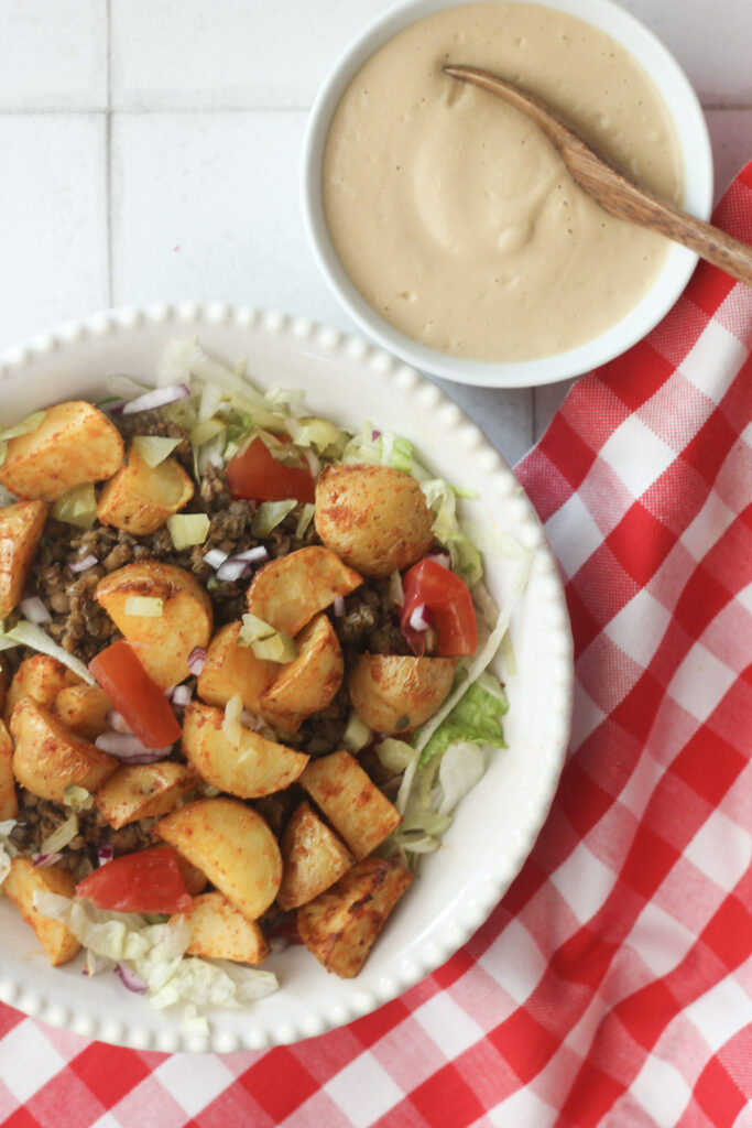 The potatoes have been added to a salad in a white bowl.